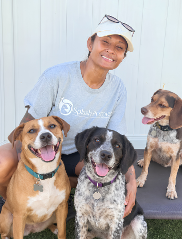 Dog trainer smiling with three happy dogs during an outdoor training session.